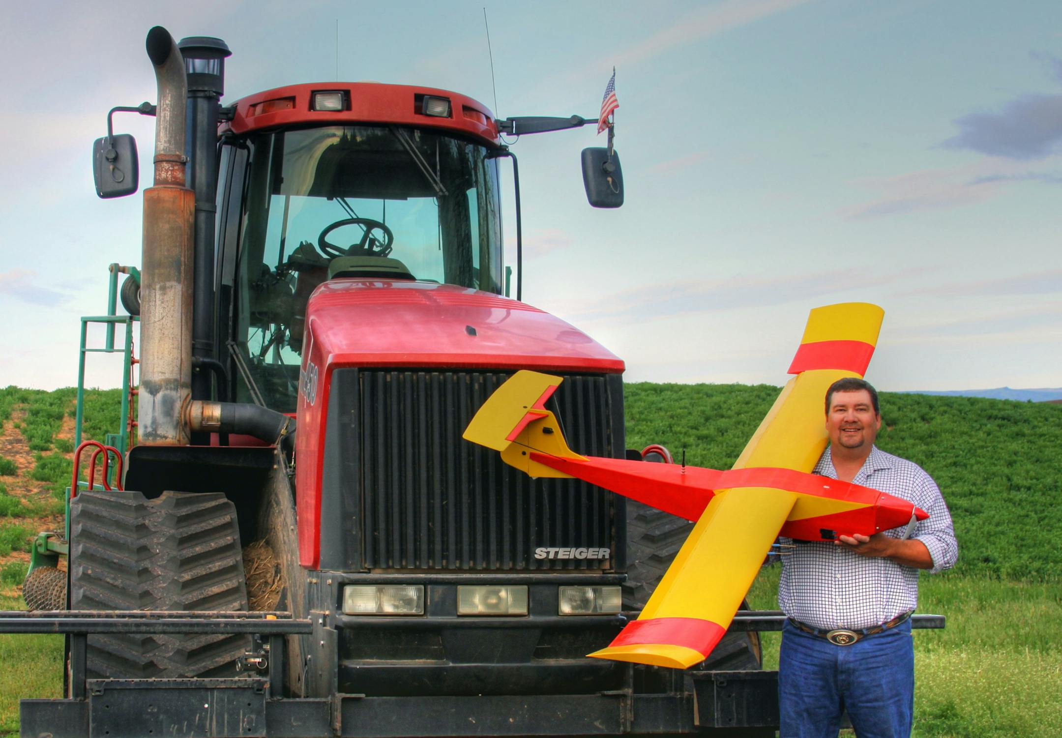 In this May 2013 photo provided by Rhonda Blair, farmer Robert Blair stands in front of his tractor holding an unmanned aircraft that he built in Kendrick, Idaho. Blair uses the home-made drone equipped with up to four cameras to √¨scout√Æ his 1,500 acres of wheat, peas, barley and alfalfa and cow pasture. (AP Photo/Courtesy of Rhonda Blair) ORG XMIT: MIN2014010118480248