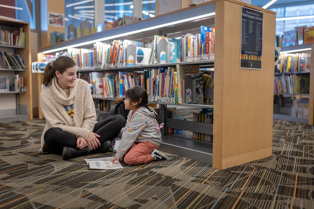 Julia Furness Rubio, left, the Office of Latine Achievement coordinator, reads with a student during a field trip to the downtown library in Minneapolis. The Office of Latine Achievement held a winter break academy that the district put on for students at a homeless shelter in Minneapolis.