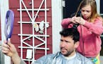 Frankie Scherer cuts the hair of her dad, Matt Scherer, in the family's backyard.