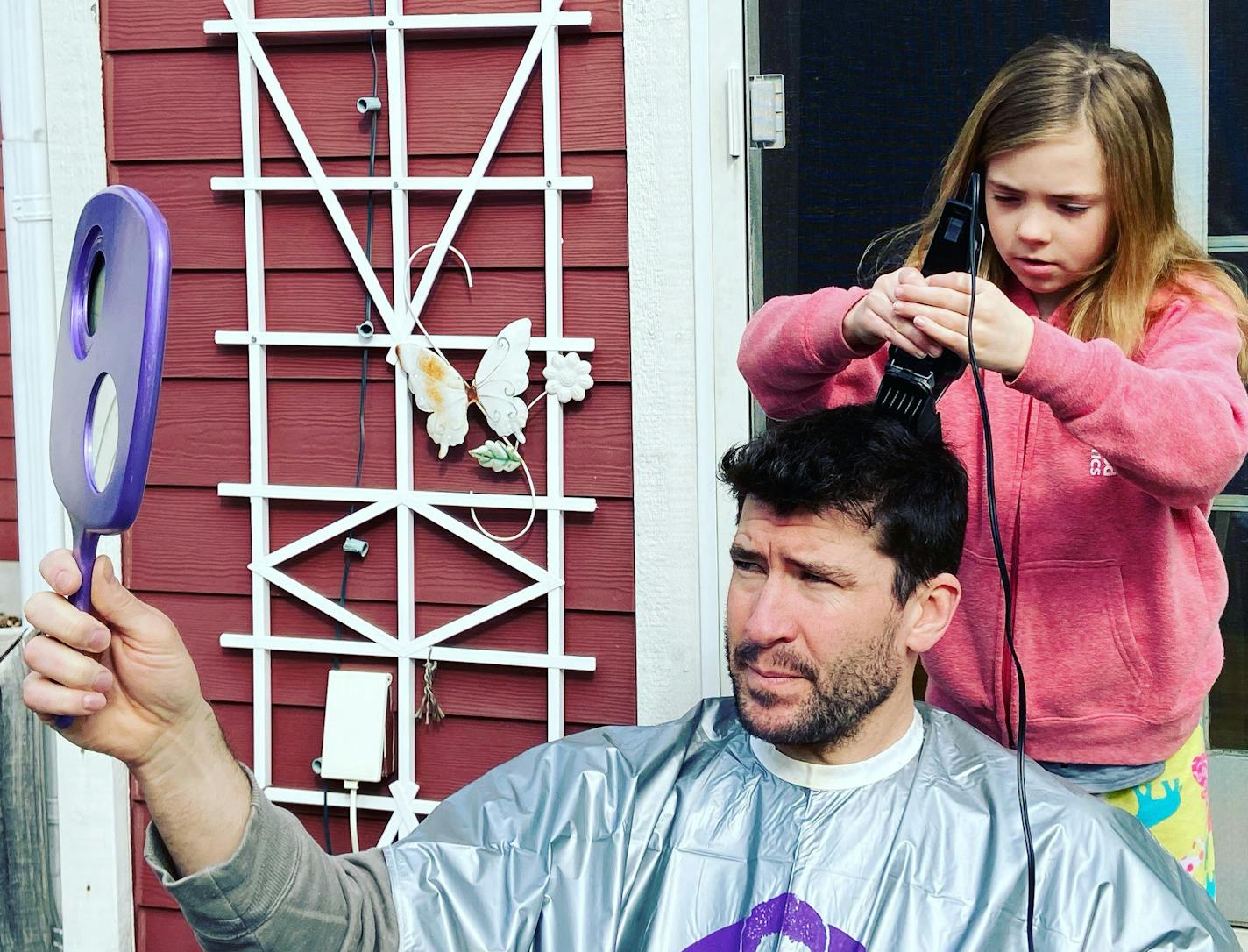 Frankie Scherer cuts the hair of her dad, Matt Scherer, in the family's backyard.