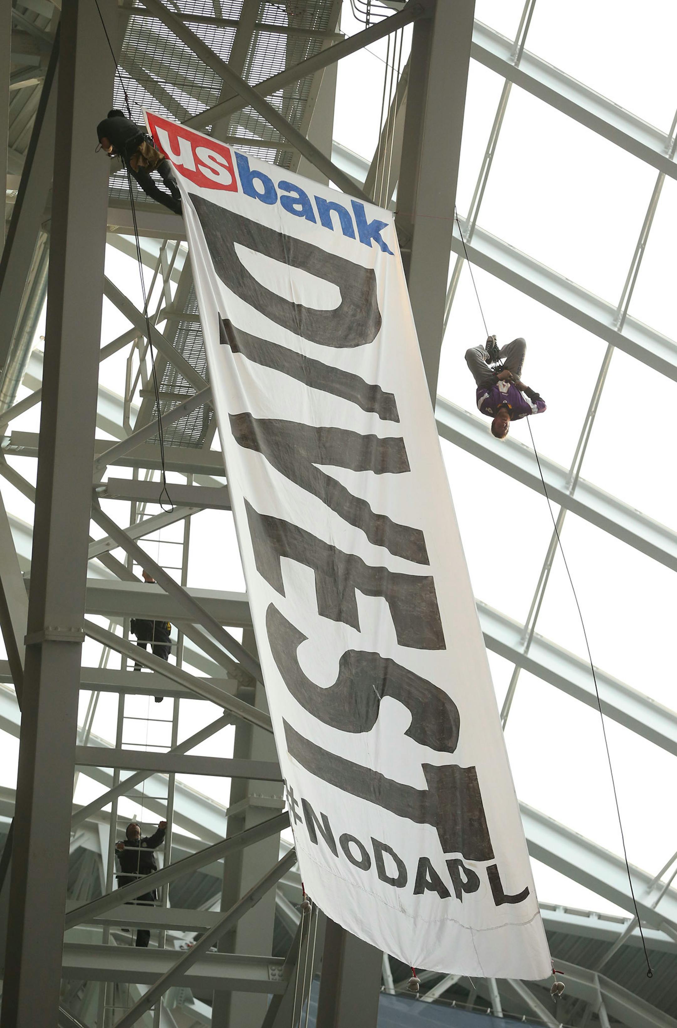 Protestors hung a banner from the catwalk of U.S. Bank Stadium calling for U.S. Bank to divest it's interests in the controversial pipeline in the Dakotas.