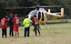 Fire Department rescue personnel stand near a department helicopter near the beach at Haleiwa, Hawaii, Friday, Jan. 15, 2016. Two Marine helicopters c