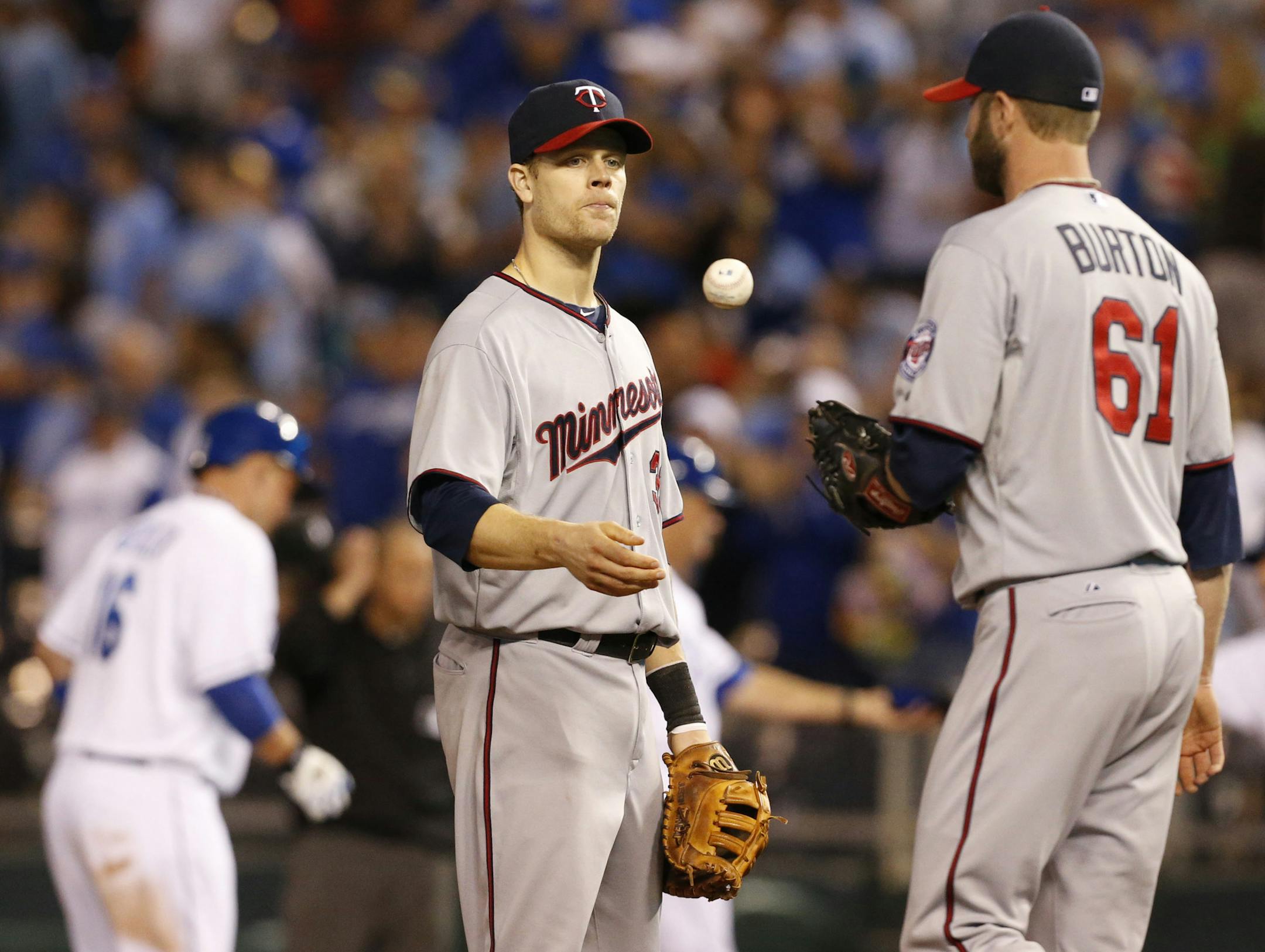 Minnesota Twins first baseman Justin Morneau, center, tosses the ball to relief pitcher Jared Burton (61) after a run scored on a hit by Kansas City Royals designated hitter Billy Butler (16) during the eighth inning of a baseball game at Kauffman Stadium in Kansas City, Mo., Thursday, June 6, 2013. (AP Photo/Orlin Wagner)