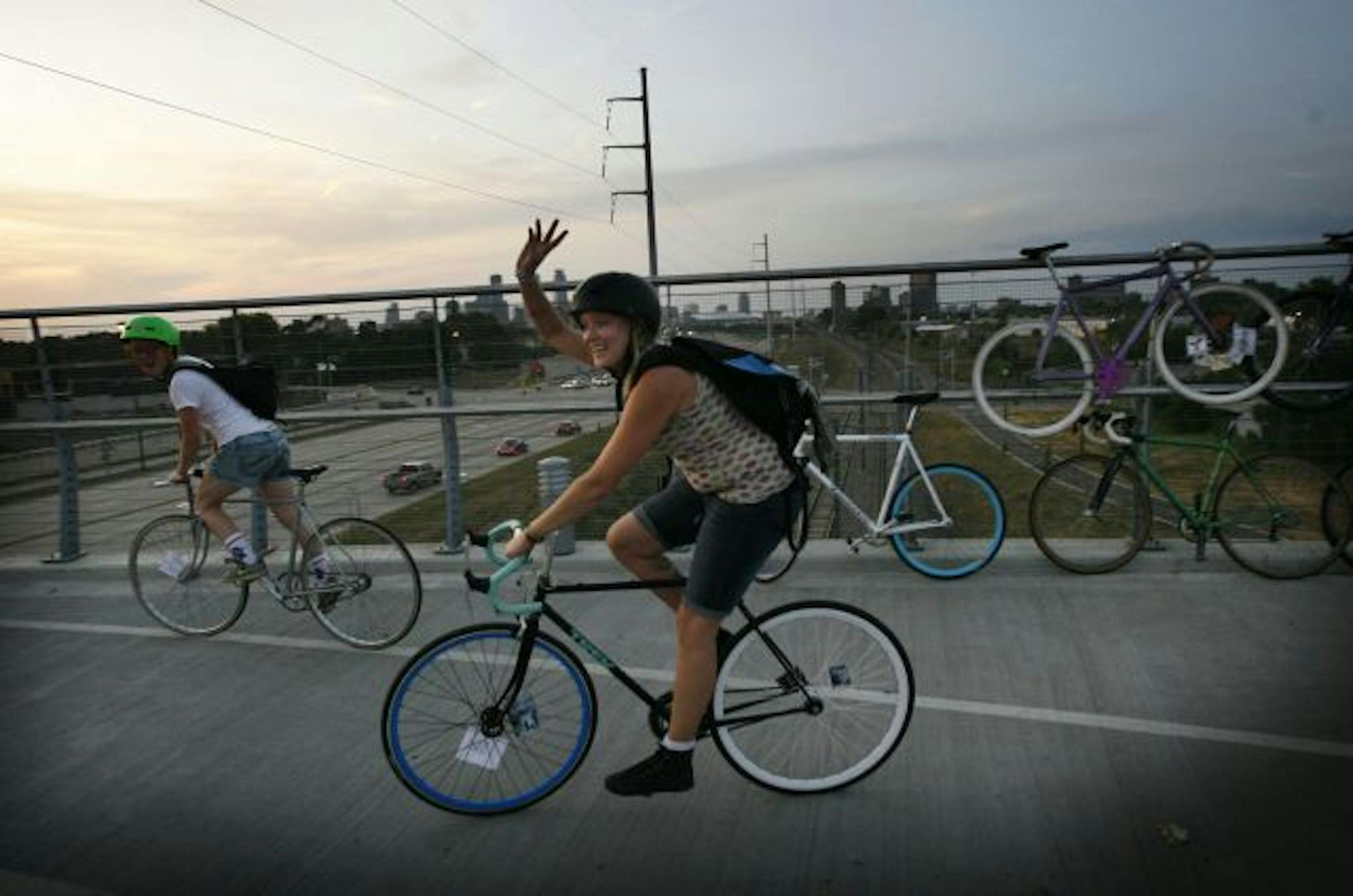 It was an all-girl alley cat scramble from the soap factory gallery to One on One bike shop Saturday. The mainly bike messenger racers made 11 checkpoints along the way, performing tasks at most. Here, Rene Nichols of Minneapolis waves and rides on after posing for a photo with a poster of Rosie the Riveter on the Sabo Bridge.