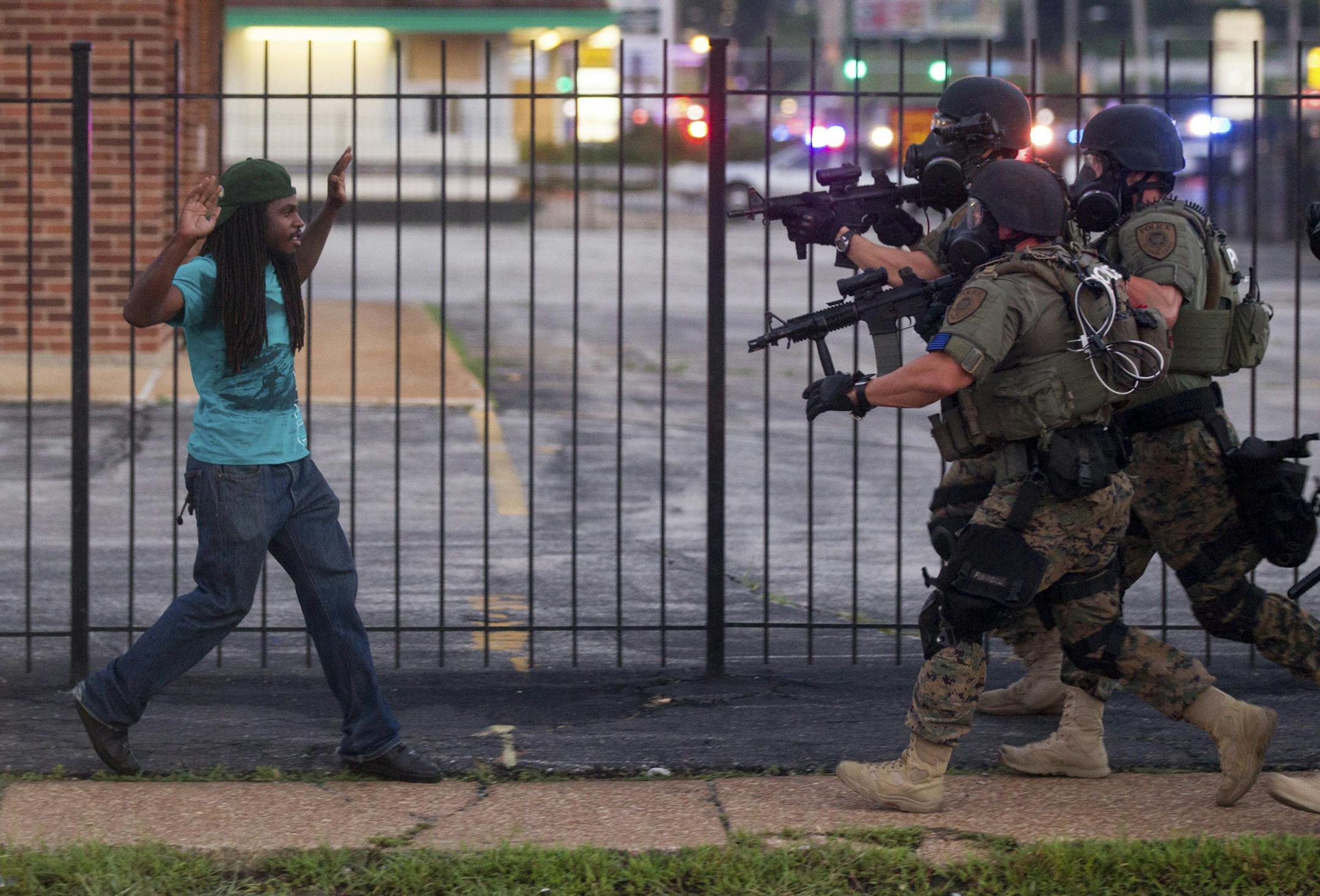 2014 YEAR IN REVIEW - FOR USE AS DESIRED -- A man backs away as law enforcement officials close in on him and eventually detain him during protests over the death of Michael Brown, an unarmed black teenager killed by a police officer, in Ferguson, Mo., Aug. 11, 2014. The Federal Bureau of Investigation said on Monday that it had opened an inquiry into the weekend shooting of Brown. (Whitney Curtis/The New York Times)