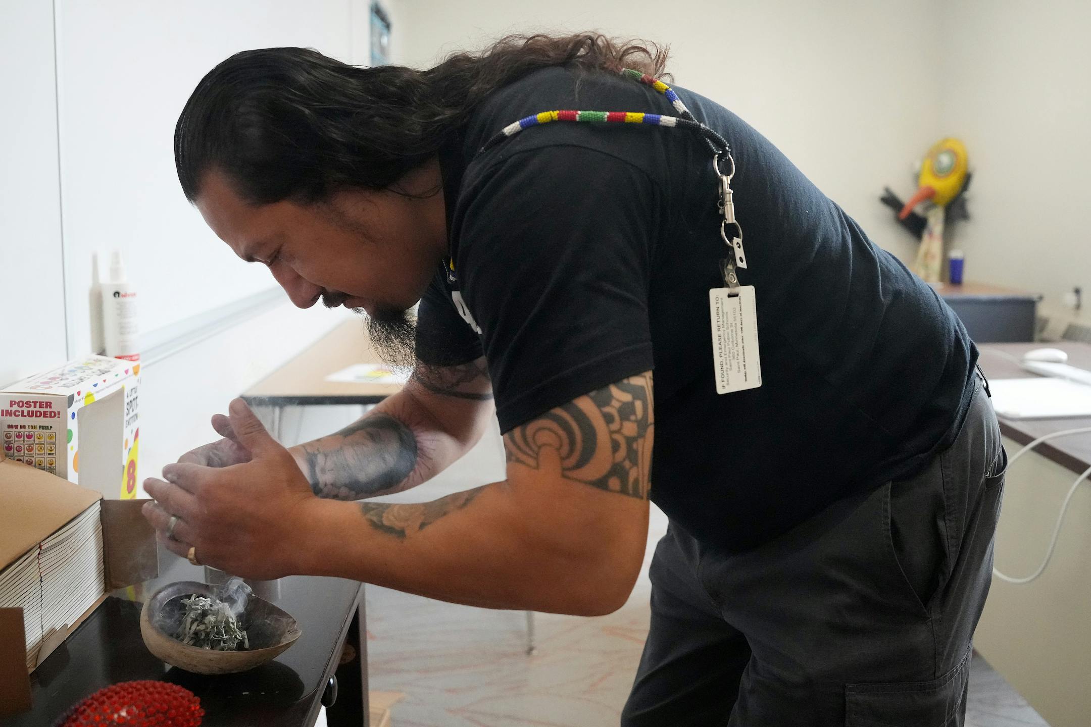 Thomas Draskovic, the kindergarten through fourth grade Lakota language and culture specialist at the American Indian Magnet School, lights a bundle of sage and cedar as he smudges the school on the first day of class in St. Paul. The school board recently enshrined smudging as district policy.
