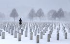 A woman visits a gravesite in the Fort Snelling National Cemetery in a snowstorm Wednesday, March 23, 2016, in Minneapolis, MN.