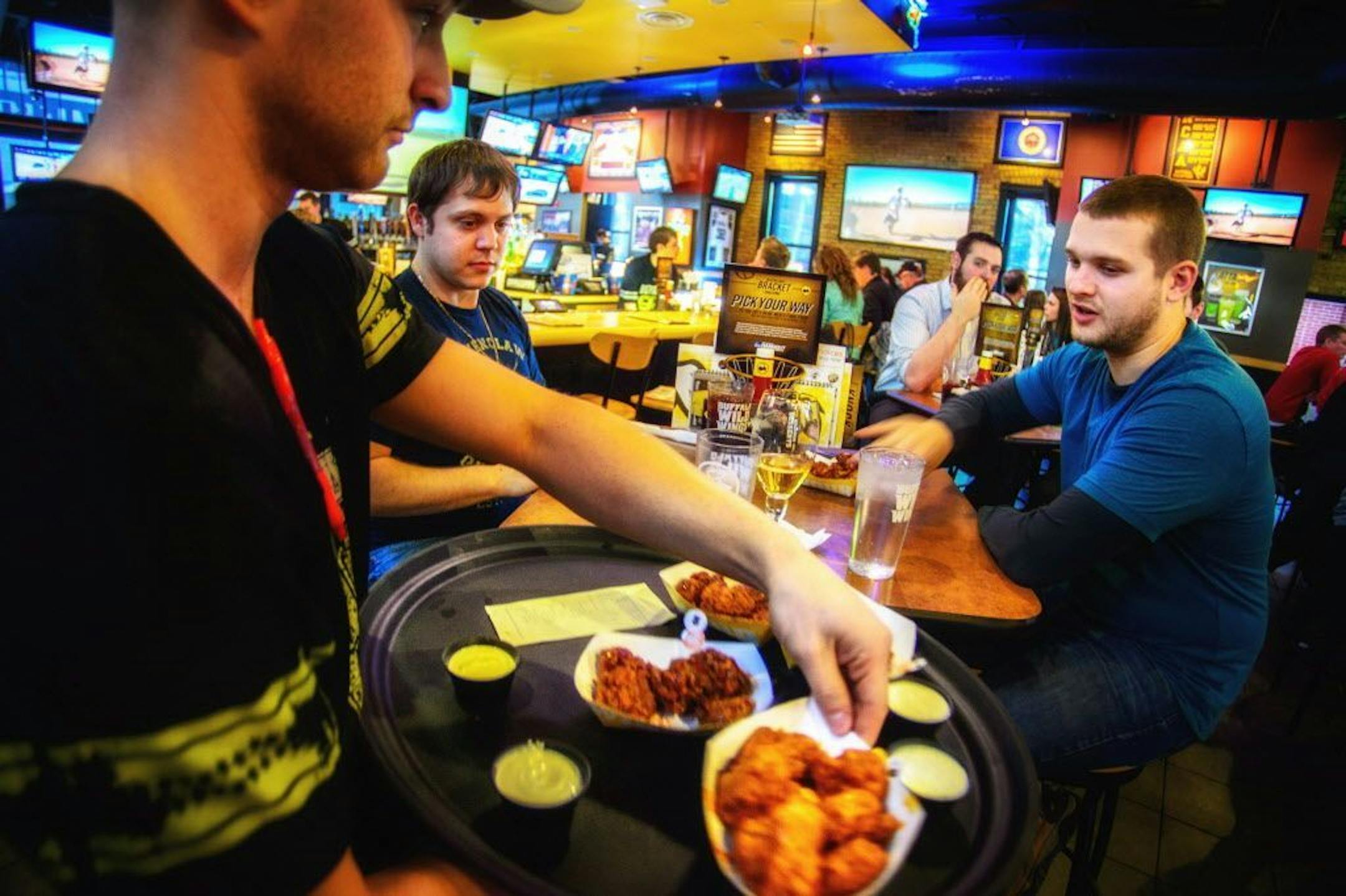 Chadwick Hamblin delivered wings to customers Frank Koslucher and Justin Munafo at the Buffalo Wild Wings at the University of Minnesota on March 20, 2014.