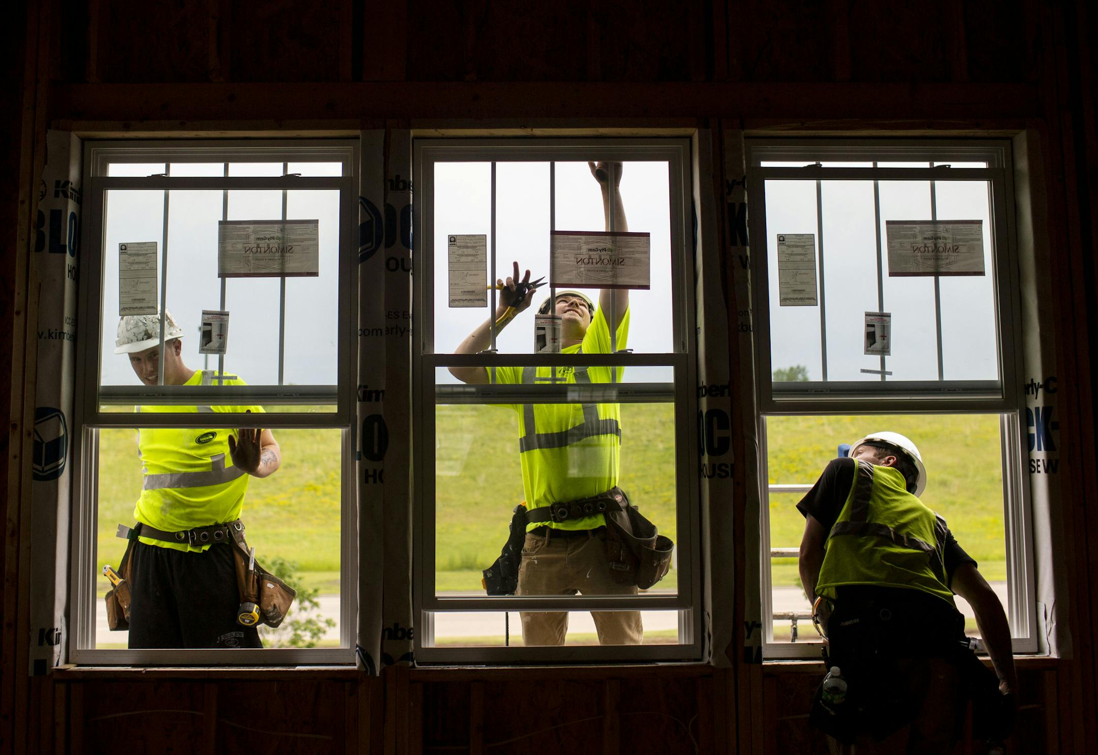(From left) Gabe Totzke, Garrett Weinberg, and Donald Hetrick install second-story windows. ] NICOLE NERI • nicole.neri@startribune.com BACKGROUND INFORMATION: Construction crews work on building homes in the Donegal neighborhood Thursday, June 27, 2019.