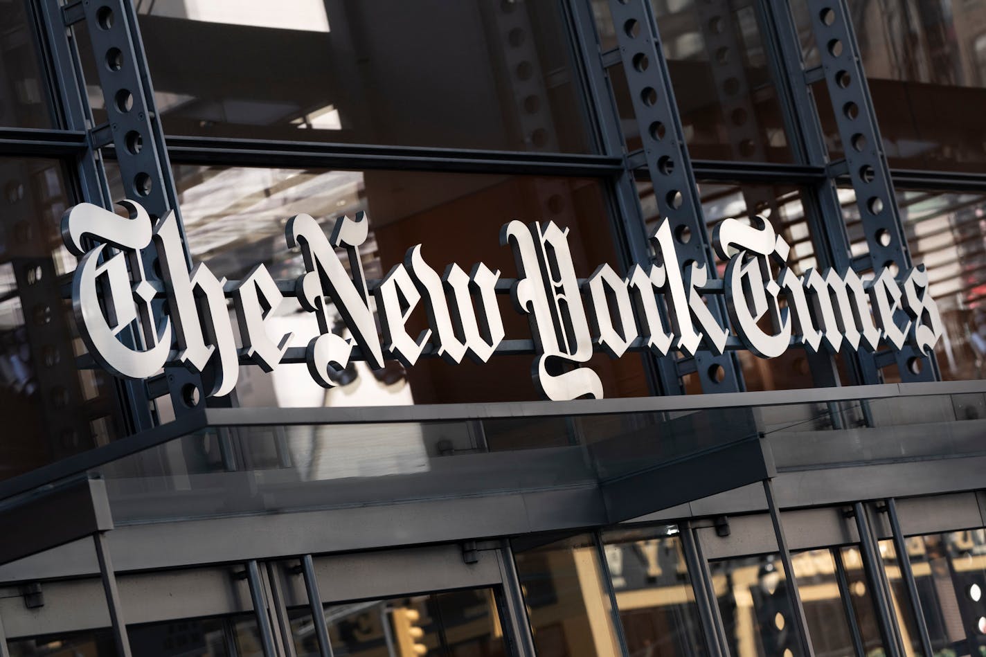 FILE - A sign for The New York Times hangs above the entrance to its building, May 6, 2021, in New York. The New York Times is getting rid of its sports department and will instead rely on sports coverage from its website The Athletic going forward, according to a report on the media company's website. The move impacts more than 35 people in the sports department. The report on Monday, July 10, 2023 said that journalists on the sports desk will move to other roles in The New York Times newsroom and that there were no planned layoffs. (AP Photo/Mark Lennihan, File)