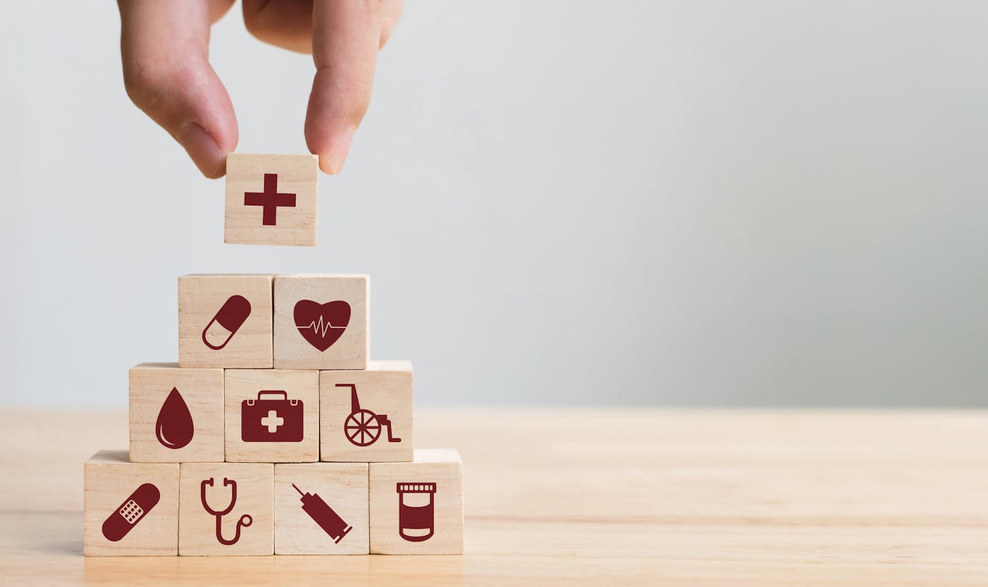 iStock
Hand arranging wood block stacking with icon healthcare medical, Insurance for your health concept