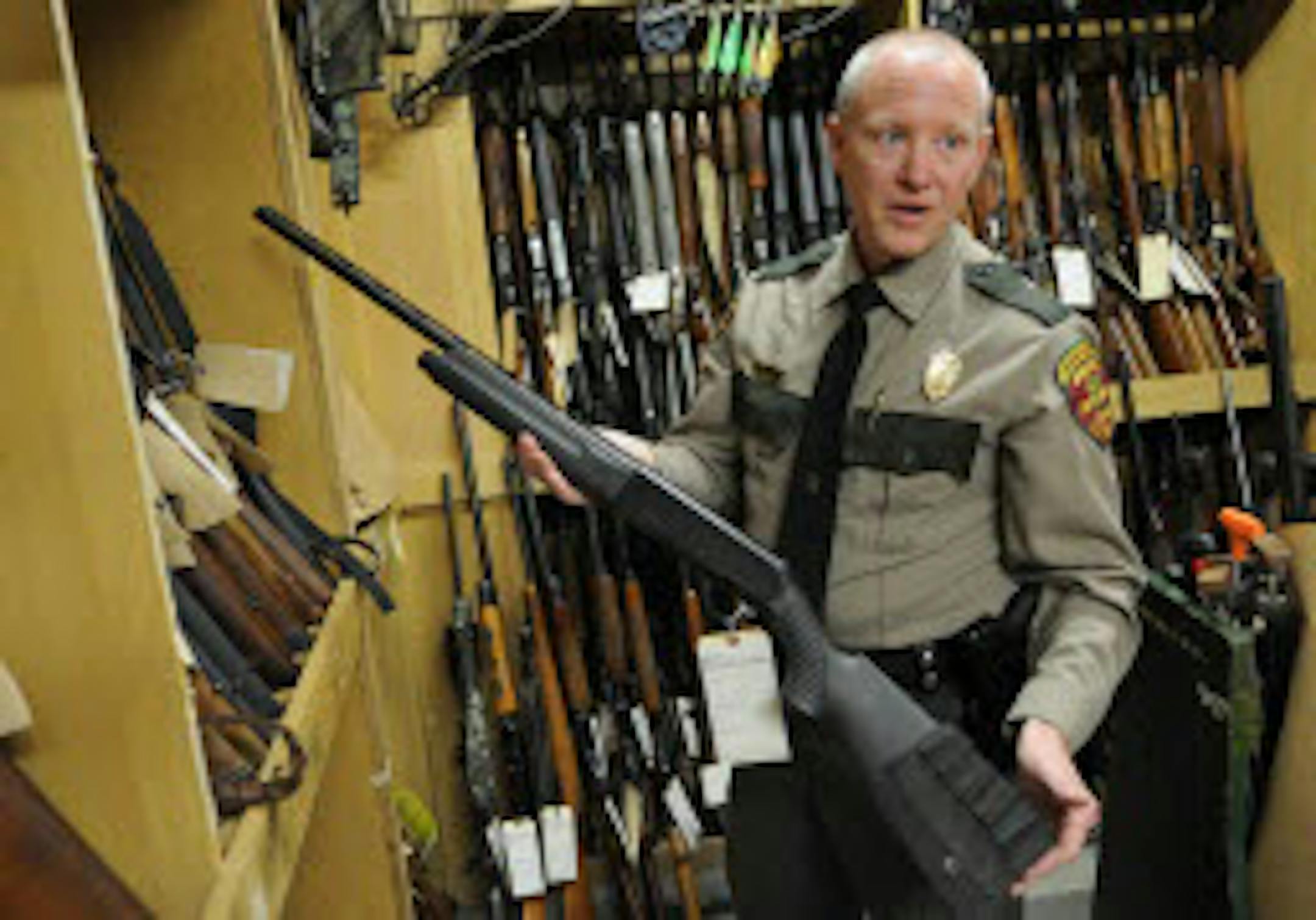 Jim Konrad, DNR enforcement chief, in a 2009 photo showing confiscated guns collected by DNR conservation officers.
