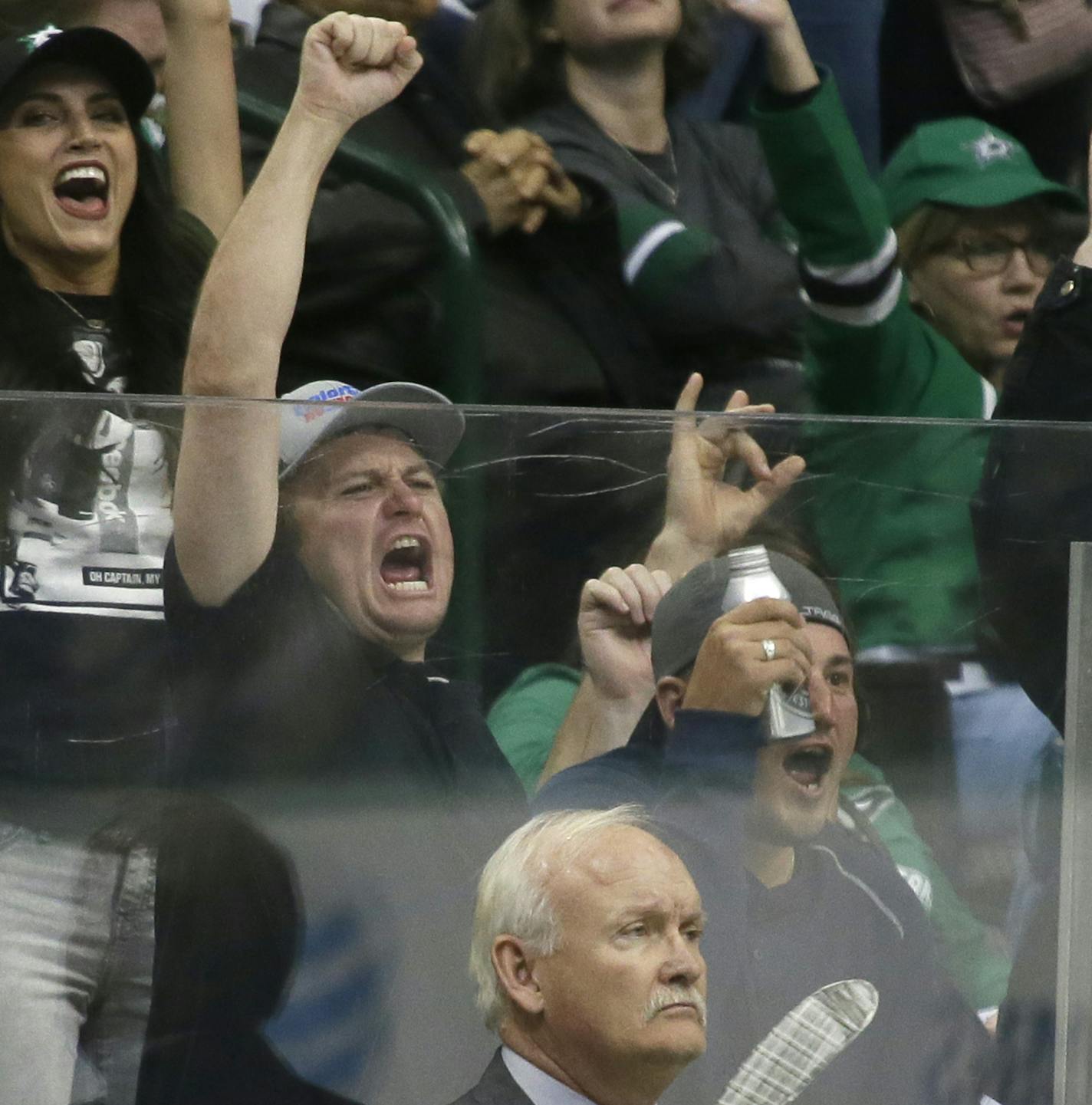 Fans cheer behind Dallas Stars coach Lindy Ruff, front, after the Stars scored a goal during the third period of Game 1 in a first-round NHL hockey Stanley Cup playoff series against the Minnesota Wild on Thursday, April 14, 2016, in Dallas. The Stars won 4-0. (AP Photo/LM Otero)