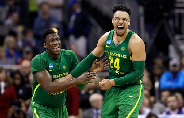 Oregon guard Dylan Ennis, left, celebrates with teammate Dillon Brooks at the end of the Midwest Regional final against Kansas in the NCAA men's colle