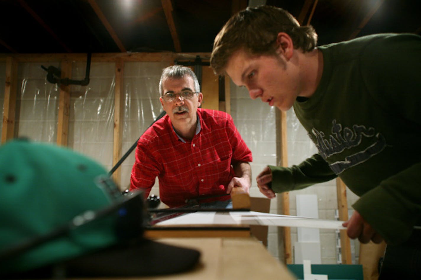 Brian Sherman, left, and Joe Phillippi cut a mat while working on a framing project that will hang in a suite at the Xcel Center. Sherman, an art teacher at Hill-Murray has glaucoma, and for the past year Phillippi, a senior at the school, has helped him with his framing business.