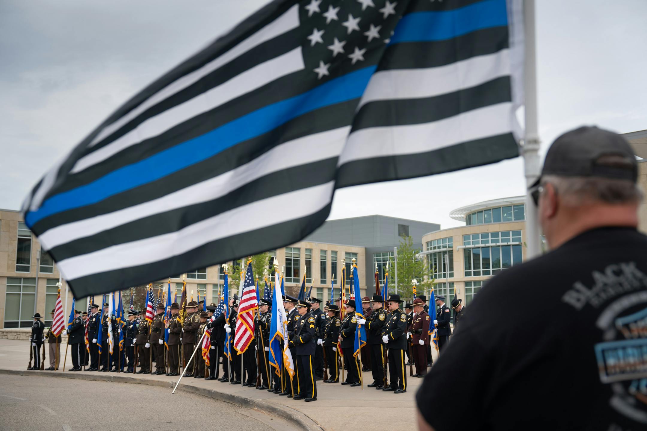 Retired New Richmond police officer Thomas Wolf held a flag outside the funderal service.  He said he wanted to honor Kaitie and all the other police officers who put their lives on the line every day Friday, May 12, 2023  Hudson, Wis.