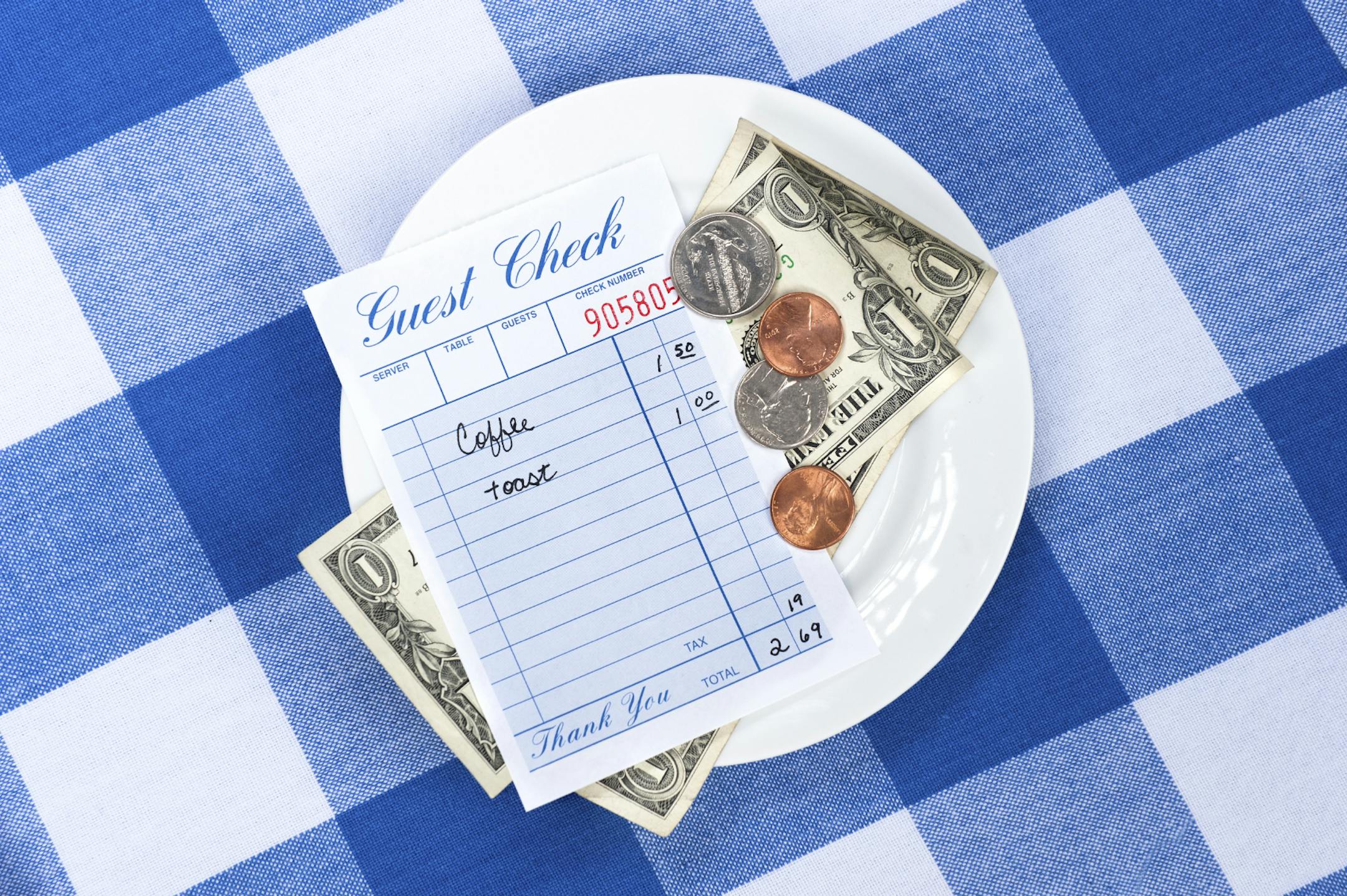 A dining check on a saucer with change from a meal payment.