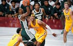 Michigan State guard Tyson Walker goes up for a shot past Minnesota guard Payton Willis, left, and forward Eric Curry (1) during the second half an NC