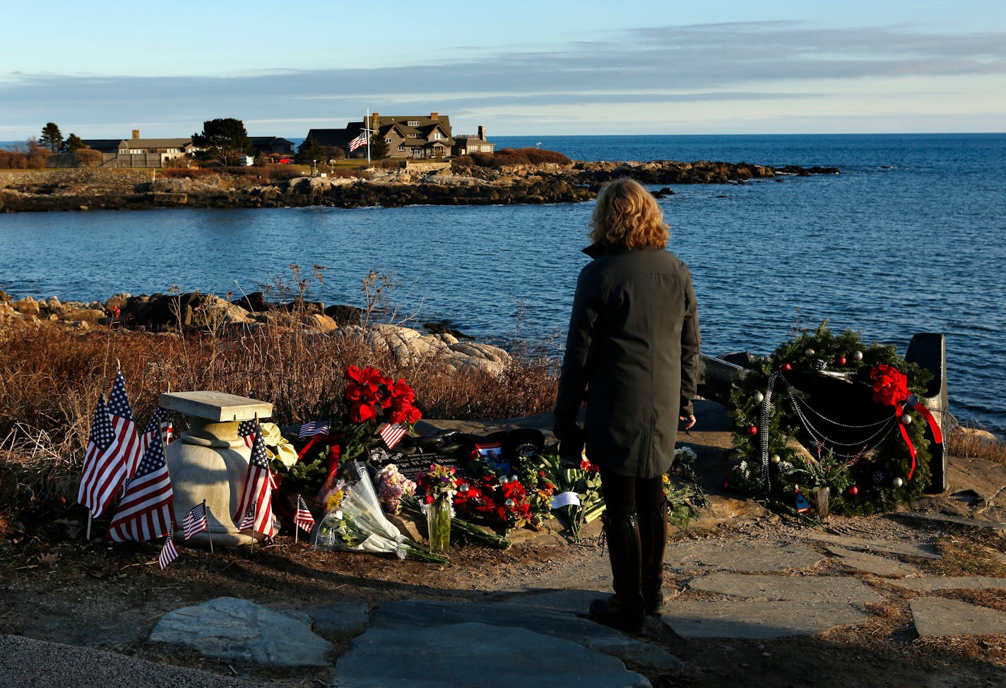 Cathy Rogers of Windham, Maine, pays her respects at a makeshift memorial for President George H. W. Bush across from Walker's Point, the Bush's summer home, Saturday, Dec. 1, 2018, in Kennebunkport, Maine. Bush died at the age of 94 on Friday, about eight months after the death of his wife, Barbara Bush.