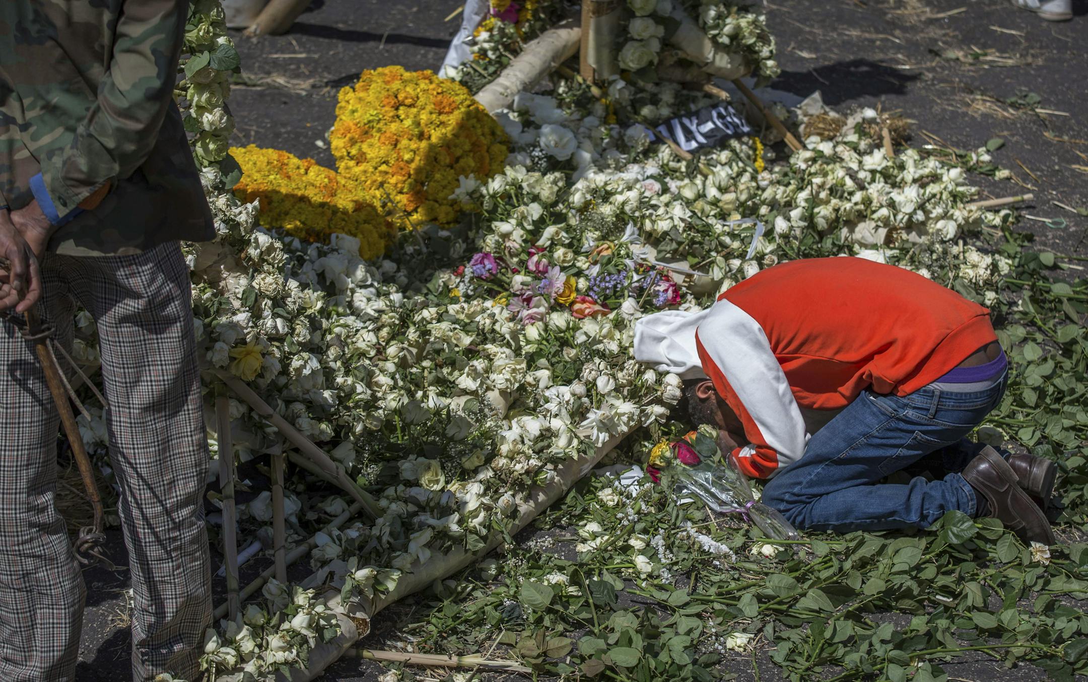 An Ethiopian relative of a crash victim mourns and grieves next to a floral tribute at the scene where the Ethiopian Airlines Boeing 737 Max 8 crashed shortly after takeoff on Sunday killing all 157 on board, near Bishoftu, south-east of Addis Ababa, in Ethiopia Friday, March 15, 2019. Analysis of the flight recorders has begun in France, the airline said Friday, while in Ethiopia officials started taking DNA samples from victims' family members to assist in identifying remains. (AP Photo/Muluge
