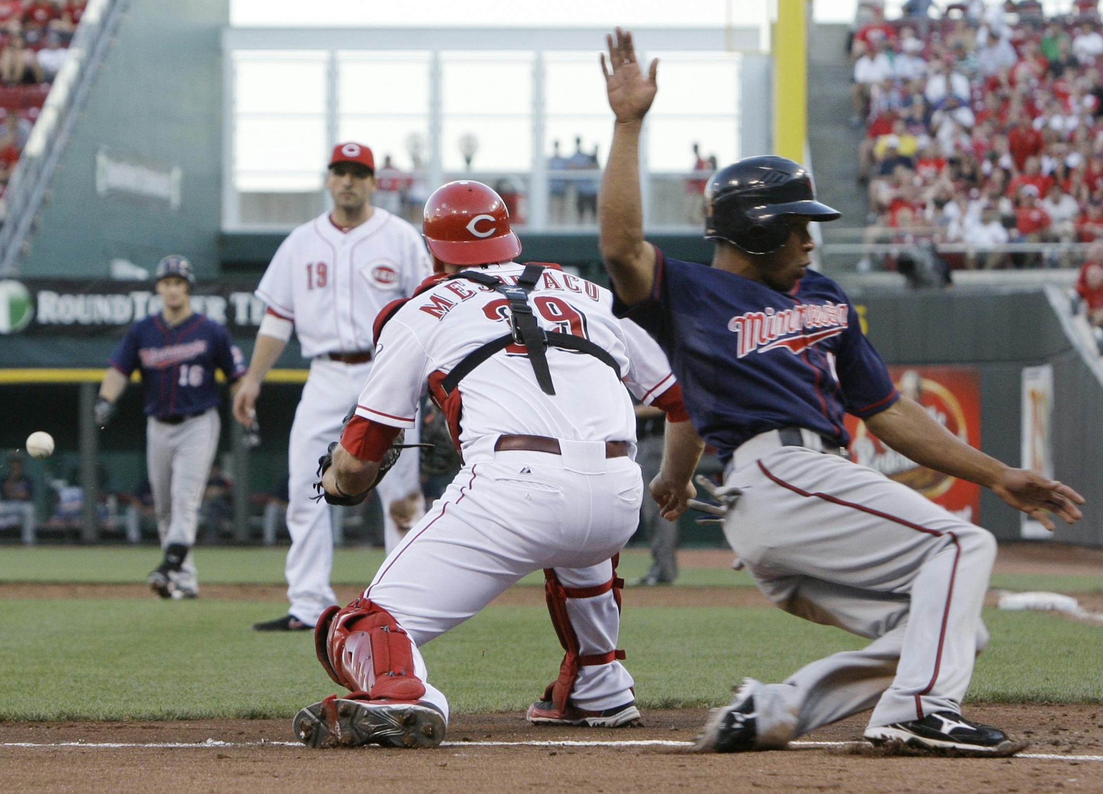 Minnesota Twins' Ben Revere, right, scores as Cincinnati Reds catcher Devin Mesoraco (39) waits for the throw in the third inning of a baseball game, Friday, June 22, 2012, in Cincinnati. Revere scored on a sacrifice fly by Josh Willingham (16). First baseman Joey Votto (19) watches.