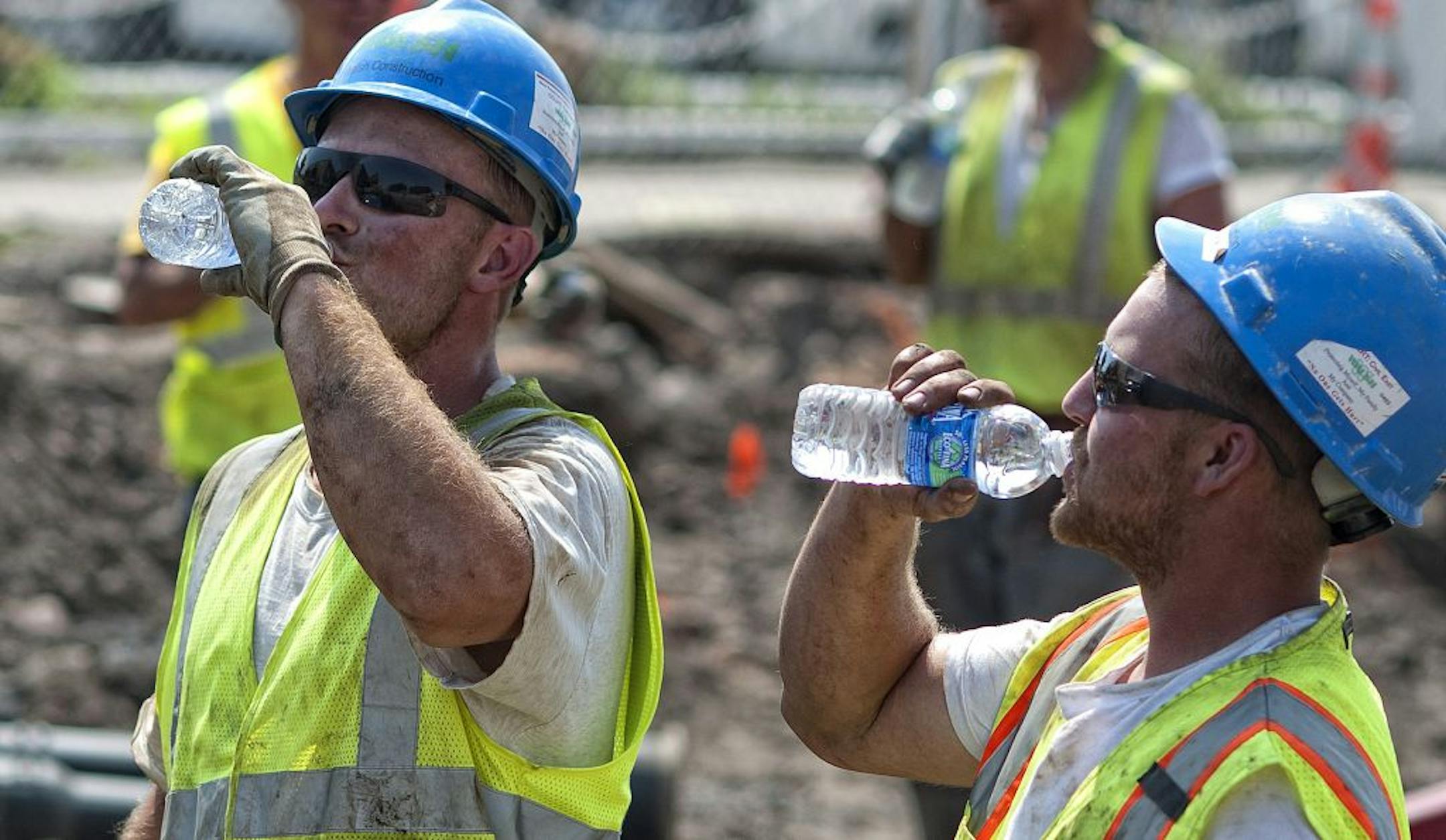 Despite triple digit temperatures Walsh Construction workers Ed Willson and Evan Anderson worked 12-hour shifts Monday and Tuesday on light rail construction along University Ave in St. Paul. They grabbed a quick bottle of water while heavy machinery removed a cut water pipe then got back to work.