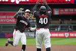 The Twins' Jose Miranda high-fives third base coach Tommy Watkins after Miranda's three-run homer with two outs in the ninth tied the score at 6. The 