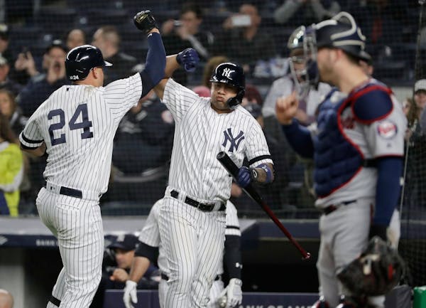 New York Yankees' Gary Sanchez, left, celebrates with teammate Gleyber Torres, center, as Twins catcher Mitch Garver looks away during the seventh inn