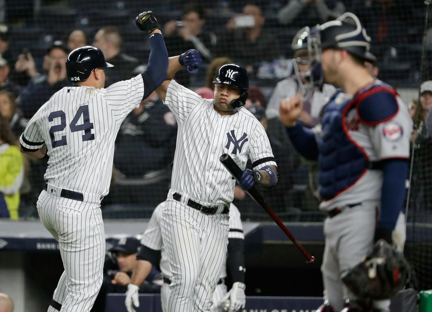 New York Yankees' Gary Sanchez, left, celebrates with teammate Gleyber Torres, center, as Twins catcher Mitch Garver looks away during the seventh inning