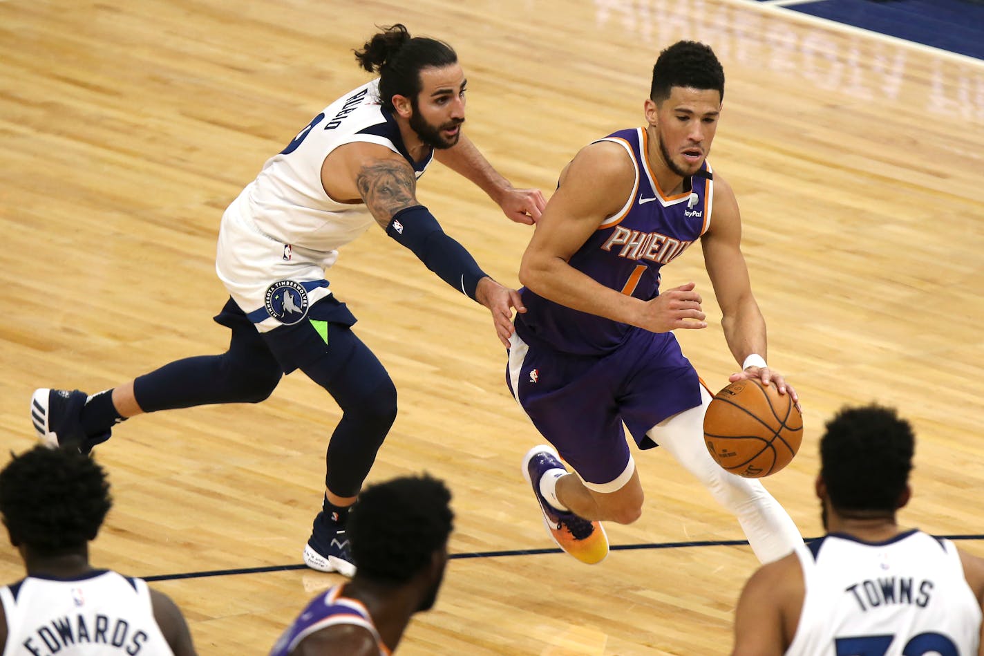 Phoenix Suns' Devin Booker (1) drives the ball past Minnesota Timberwolves' Ricky Rubio (9) in the first half of an NBA basketball game, Sunday, Feb. 28, 2021, in Minneapolis. (AP Photo/Stacy Bengs)