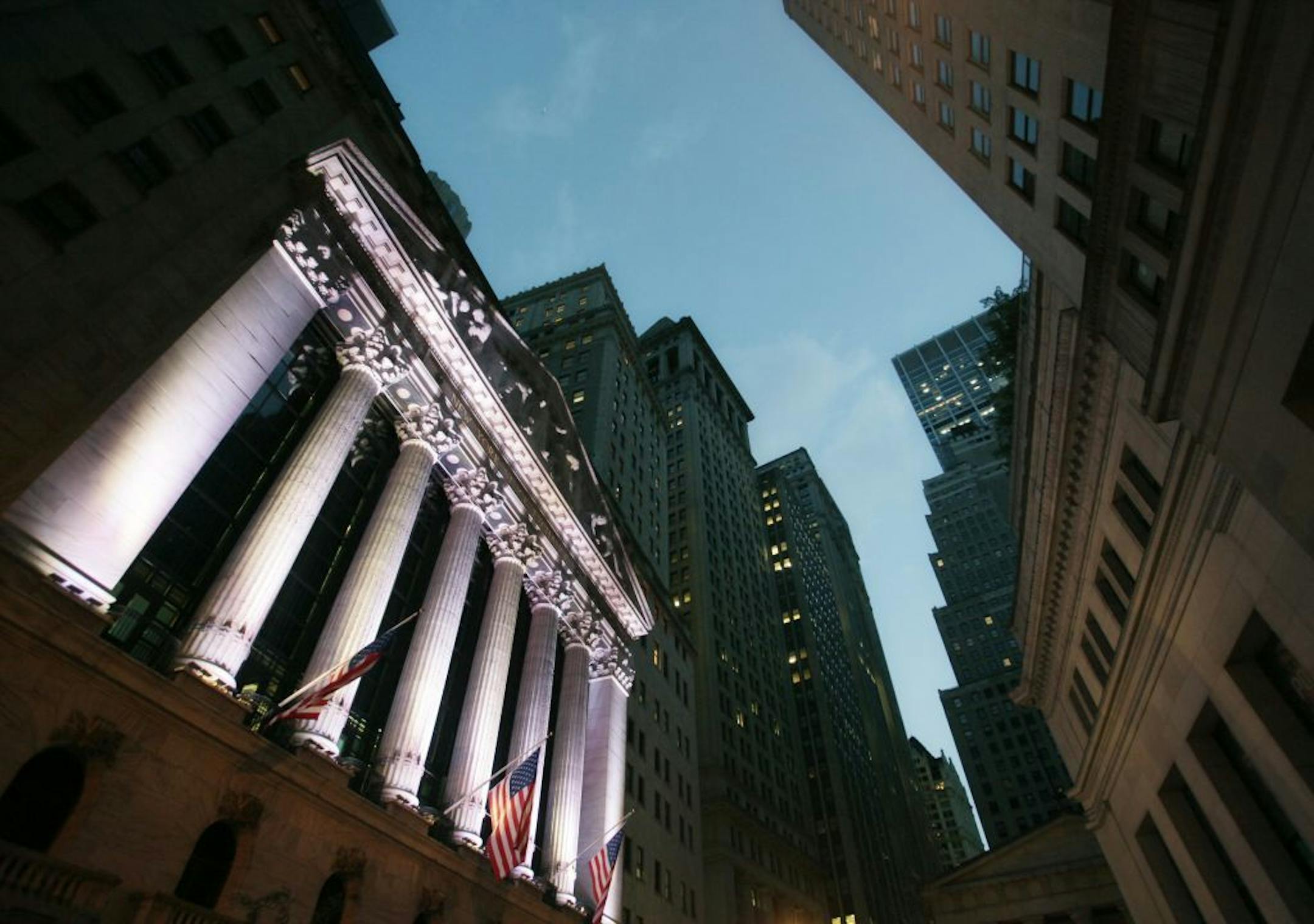 FILE - In this Wednesday, Oct. 8, 2014, file photo, American flags fly in front of the New York Stock Exchange. World stock markets were mixed on Thursday, Dec. 28, 2017, in quiet post-Christmas holiday trading. Strong economic data from Asia and the U.S. boosted investor confidence in some markets.
