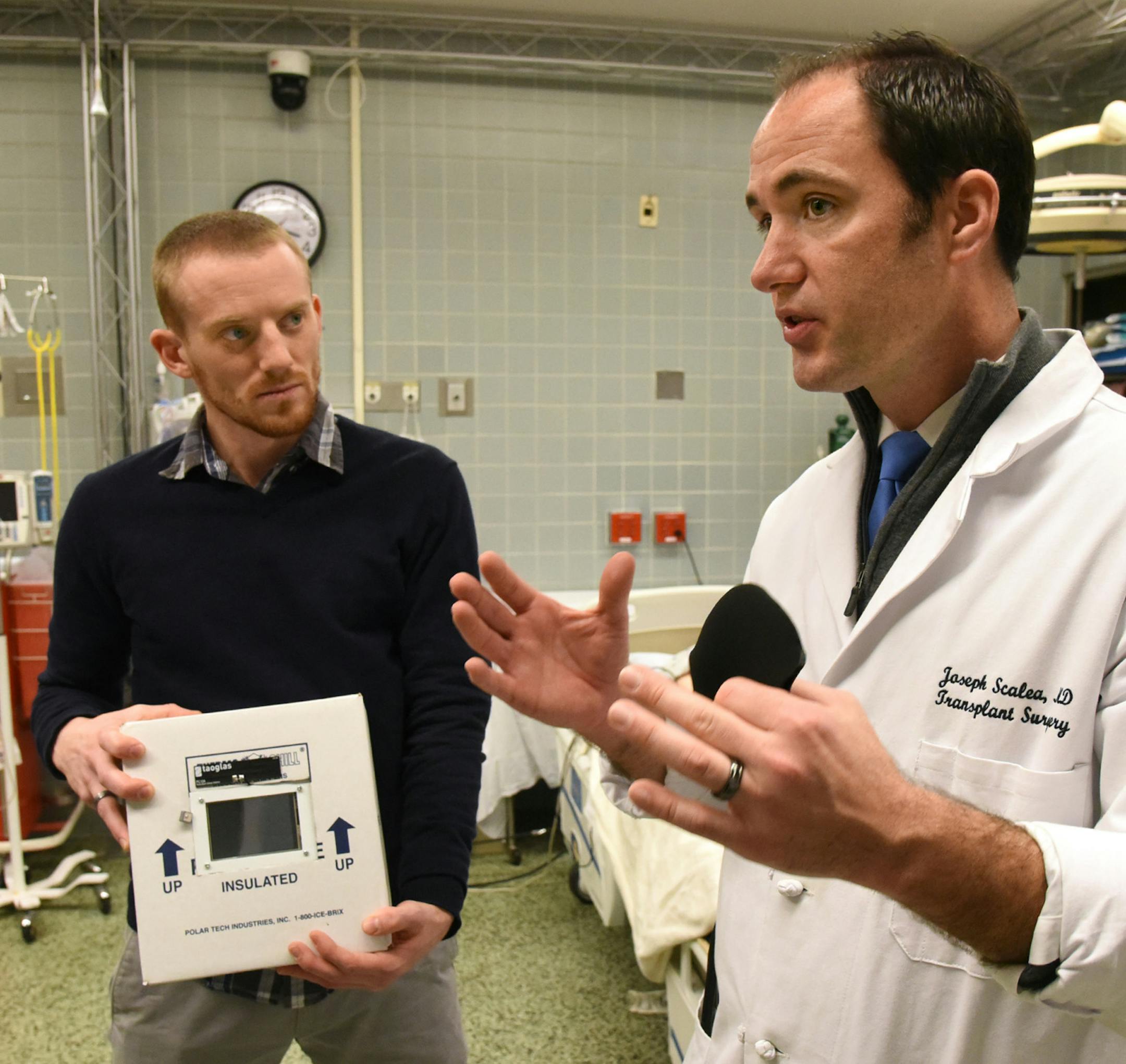 Dr. Joseph Scalea, a transplant surgeon and University of Maryland professor, right, holds a prototype organ monitoring device as he discusses using drones to deliver organs with Stephen Restaino, a senior research engineer at the Maryland Development Center, left. (Amy Davis/Baltimore Sun Media Group/TNS)