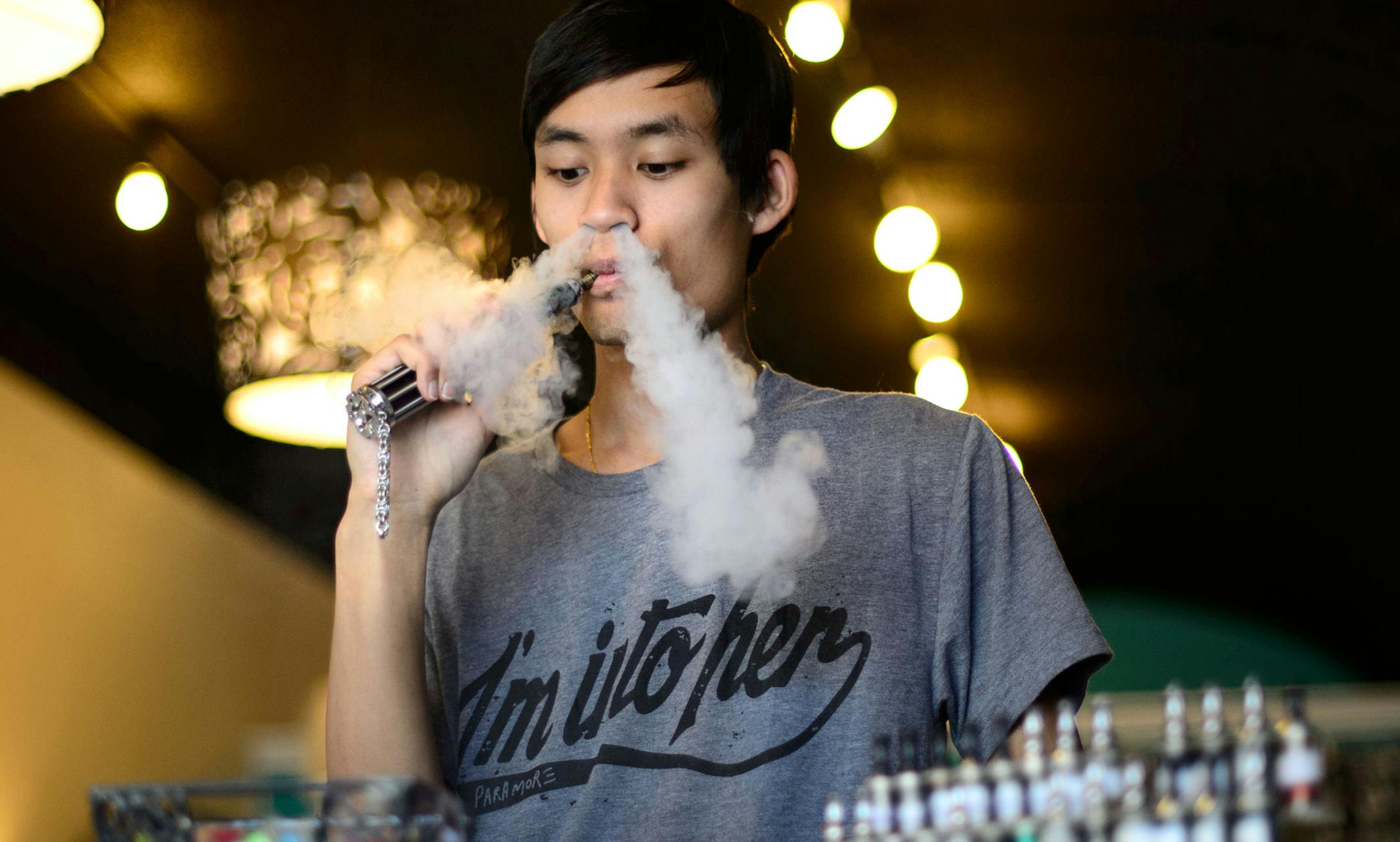 Jonny Ny “vaped” behind the counter at Uptown Vapor Shoppe. U cancer researchers are studying what exposure there may be to nicotine and toxins.