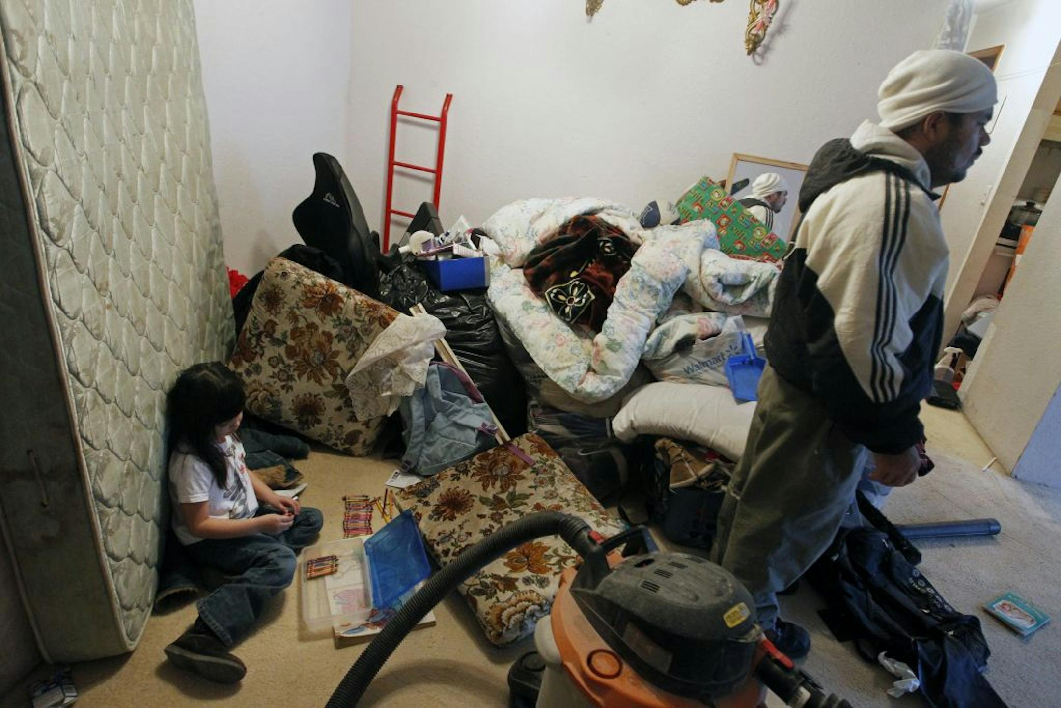 Country Village Apartments resident Jesus Escobar, right, was given short notice to move his furnishings out of the bedrooms so carpet padding could be changed.