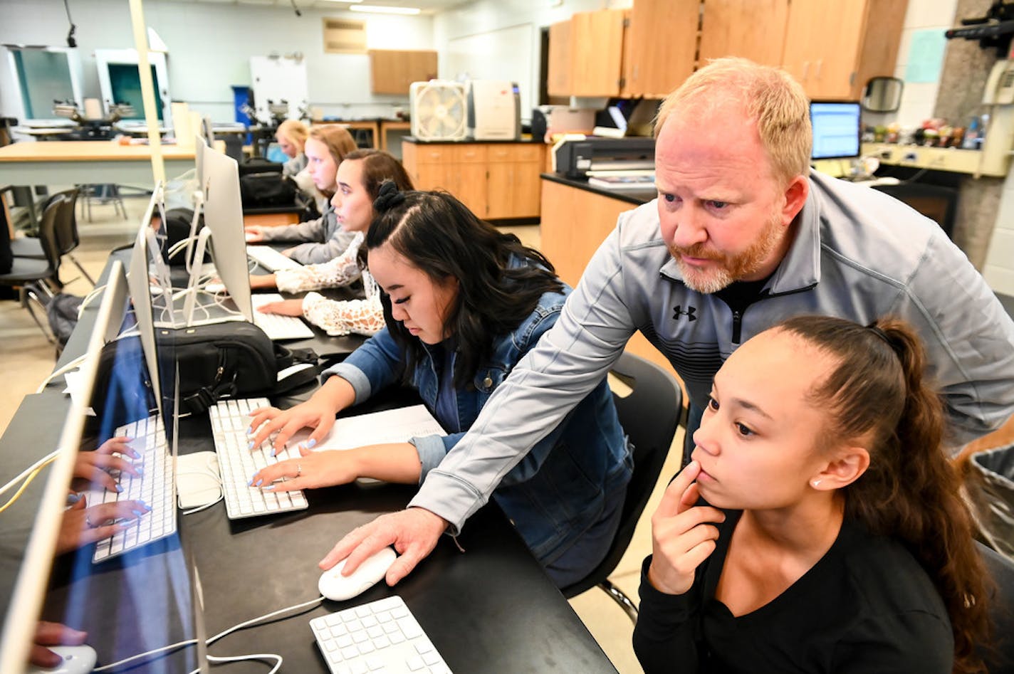 Anoka High teacher Paul Heida helped sophomore Ebony Elliott, bottom right, with illustration software during yearbook class Tuesday. Last year, statewide high school graduation rates hit a record high - with nearly 83 percent earning their diploma on time.