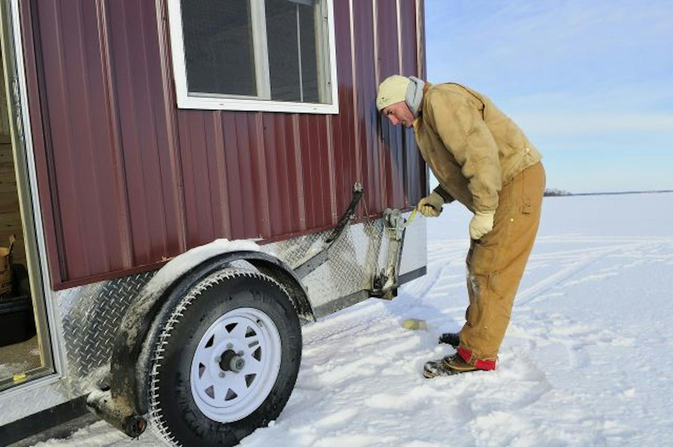 Lindy Frasl of Fort Ripley cranked one of three winches used to lower his home-built ice fishing house during its maiden ice fishing voyage.