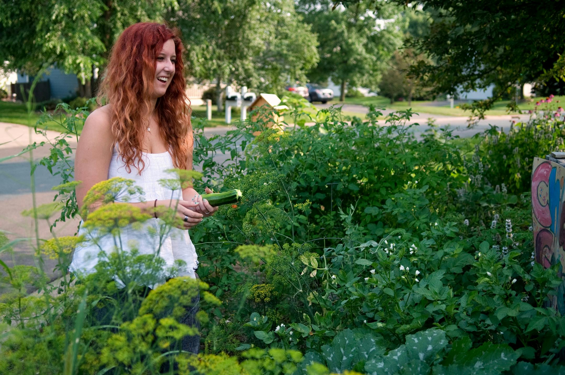 Andrea Schoenherr, 23, picks a ripe zucchini from the plant in the family garden.