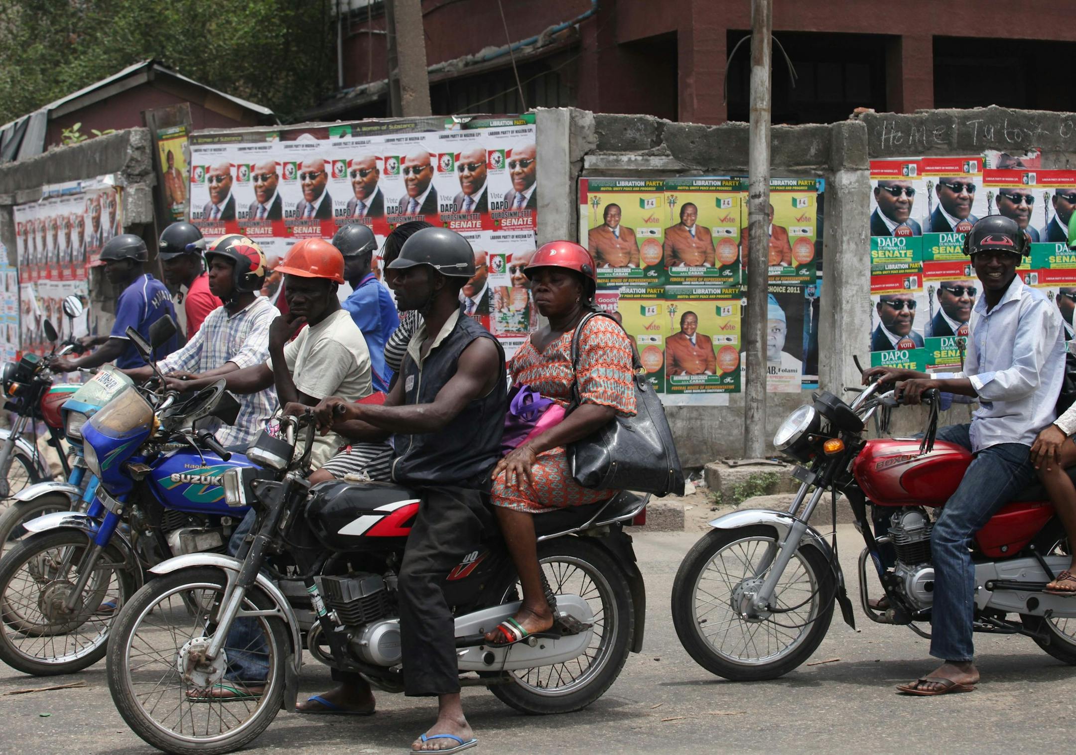 Motorcyclists wait at a traffic stop in front of election campaign posters in Yaba, Lagos, Nigeria, Wednesday, March 30, 2011. Nigeria's police force says it is deploying more officers ahead of elections which begin Saturday in Africa's most populous nation. (AP Photo/Sunday Alamba)