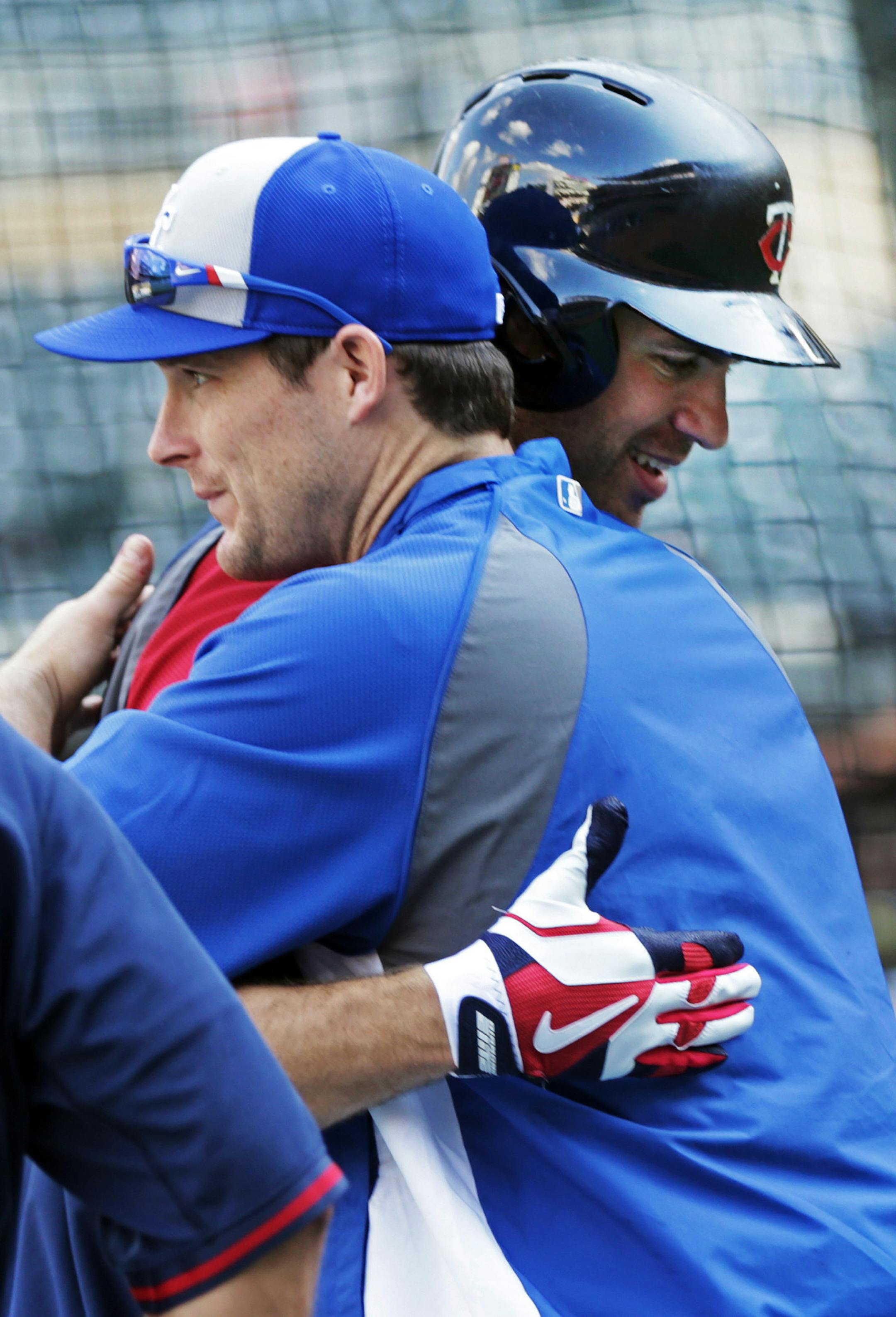 Minnesota Twins' Joe Mauer, right, and a former teammate, Kansas City Royals' Josh Willingham, hug during warm-ups for a baseball game, Friday, Aug. 15, 2014, in Minneapolis. Willingham was recently traded by the Twins to the Royals. (AP Photo/Jim Mone)