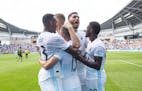 Teammates swarm Minnesota FC midfielder Ethan Finlay (13) after he hit the games only goal on a penalty kick in the 90'+ minute to lift the Loons over