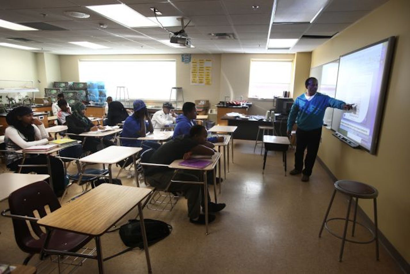 Biology teacher Deraje Daba, right, leads a unit on genetics for high school students at Higher Ground Academy, where there are no metal detectors nor police officers roaming the halls. "It's like growing up on a Cul-de-sac... where moms know everyone," said An-Her Ankhu-Ra, the school's citizenship developments coordinator, speaking of community. "Imagine that in a school."