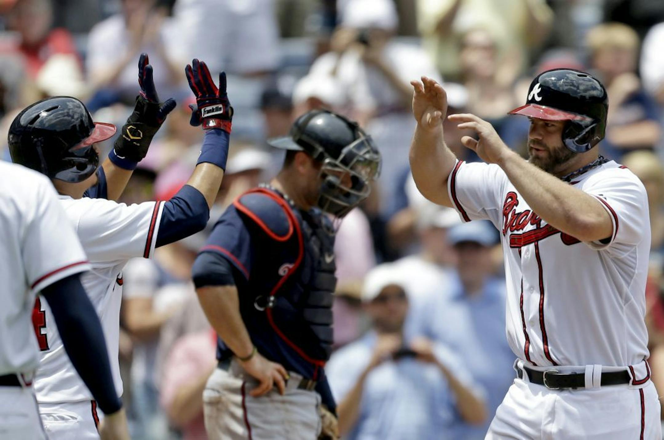 Atlanta Braves' Evan Gattis, right, high-fives teammate Ramiro Pena after hitting a grand slam in the fourth inning of a baseball game as Minnesota Twins catcher Ryan Doumit, center rear, stands at home plate, Wednesday, May 22, 2013, in Atlanta.