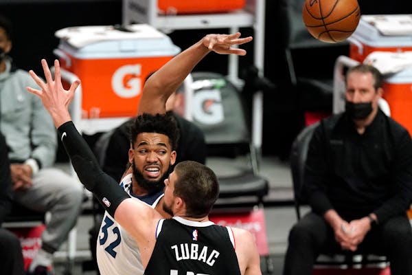 Minnesota Timberwolves center Karl-Anthony Towns, left, passes the bar while under pressure from Los Angeles Clippers center Ivica Zubac during the fi
