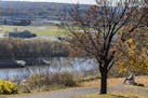 A man on a bench gets a view of the Mississippi River at Indian Mounds Park.