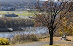 A man on a bench gets a view of the Mississippi River at Indian Mounds Park.