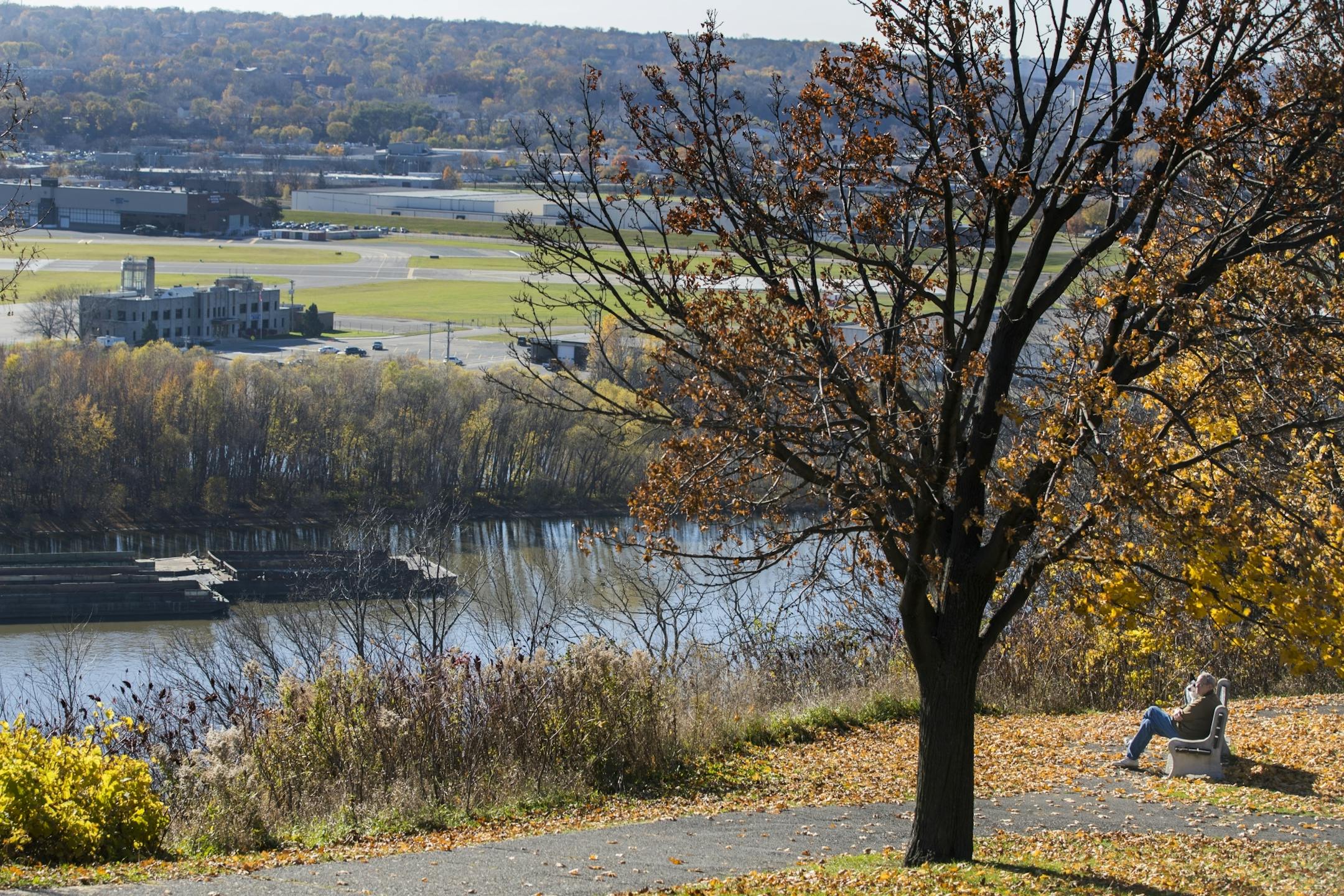 A man on a bench gets a view of the Mississippi River at Indian Mounds Park.