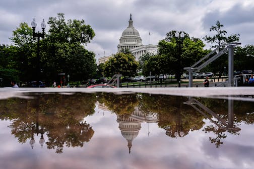 The U.S. Capitol is reflected in a puddle outside of the Rayburn House Office Building on July 16 on Capitol Hill in Washington.