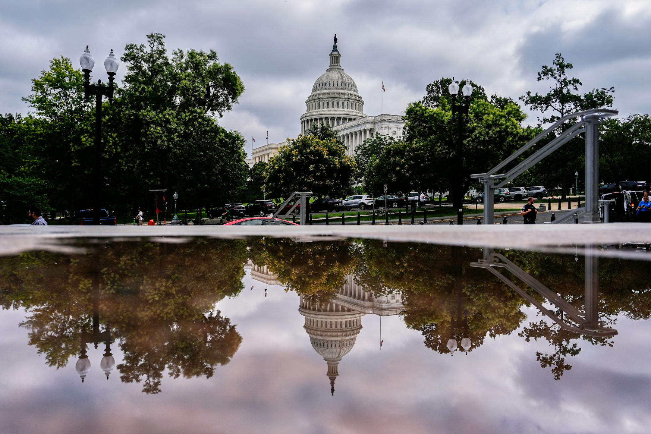 The U.S. Capitol is reflected in a puddle outside of the Rayburn House Office Building on July 16 on Capitol Hill in Washington.