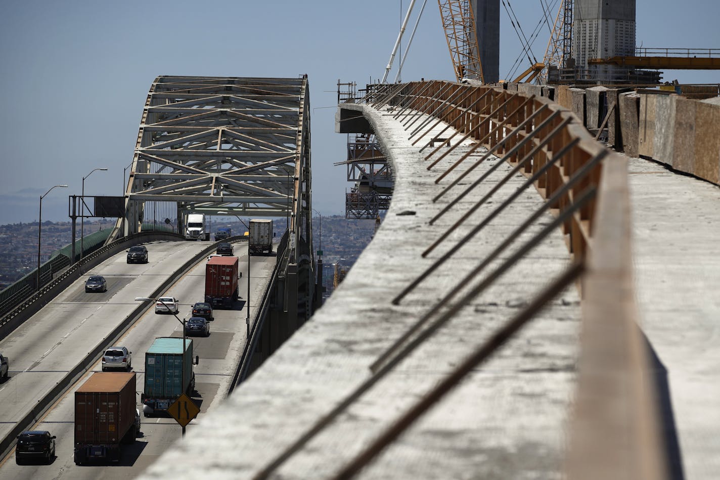 FILE - In this July 2, 2018, file photo, traffic moves on the old Gerald Desmond Bridge next to its replacement bridge under construction in Long Beach, Calif. President Donald Trump pronounced himself eager to work with Congress on a plan to rebuild America&#x2019;s crumbling roads and bridges, but offered no specifics during his State of the Union speech on what kind of deal he would back. (AP Photo/Jae C. Hong, File)