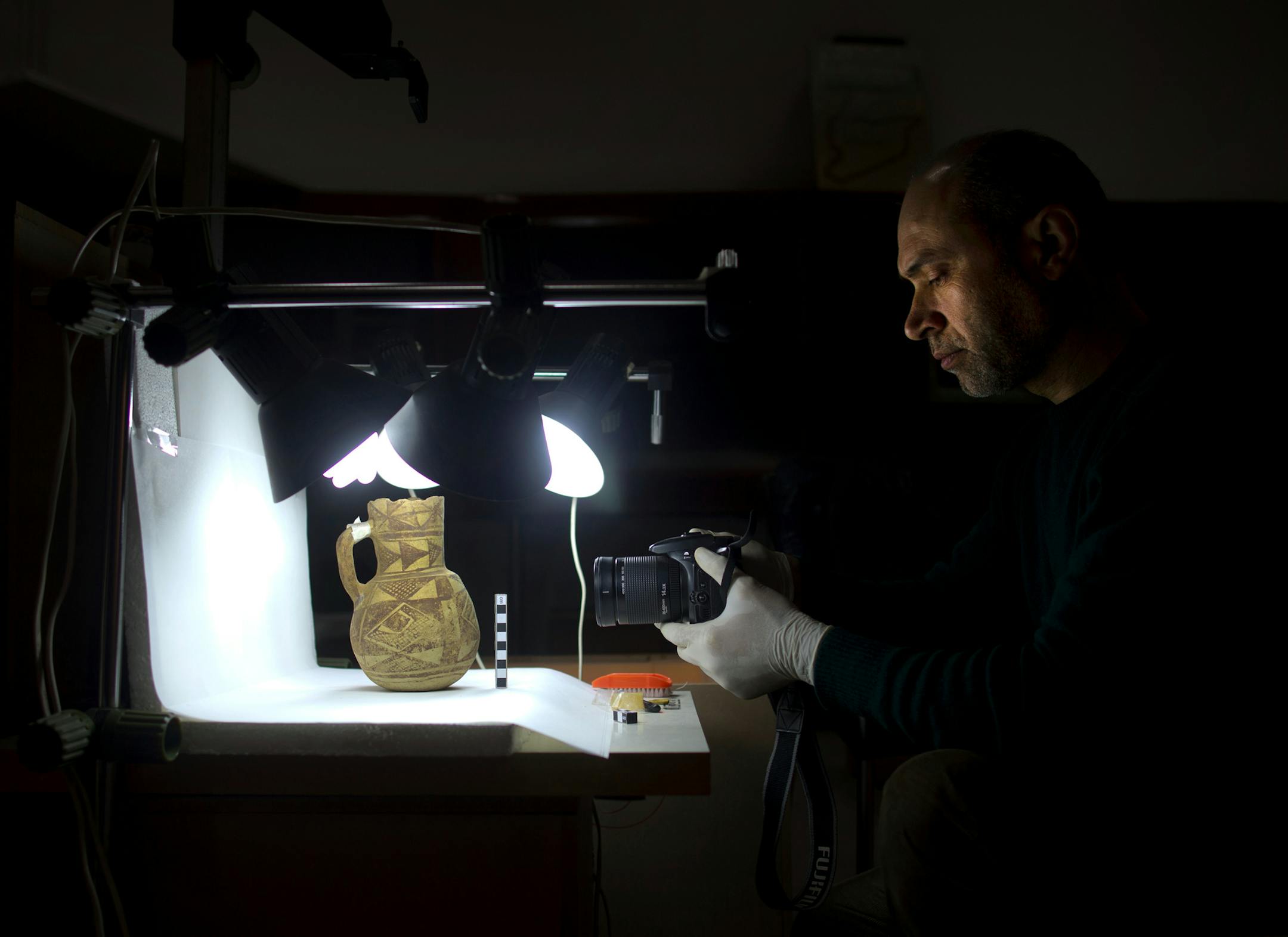In this Tuesday, Feb. 23, 2016 photo, Jihad Abu Kahrlah, an archeologist at the National Museum in Damascus, Syria works on preserving artifacts rescued from the Daraa Museum in southern Syria. Faced with the Islamic State group onslaught and destruction by looters, Syrian antiquities authorities succeeded in evacuating hundreds of thousands of artifacts from museums around the country to safety in Damascus. (AP Photo/Hassan Ammar)